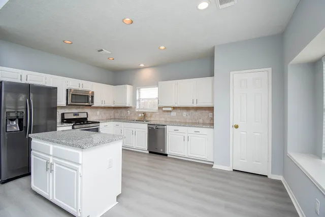 a kitchen with white cabinets and stainless steel appliances