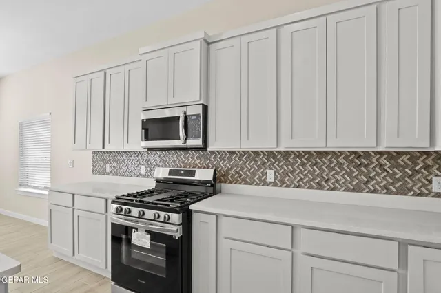 a kitchen with white cabinets and a stove top oven