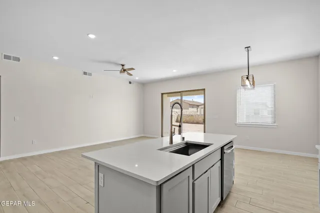 a kitchen with a sink dishwasher and a refrigerator with wooden floor