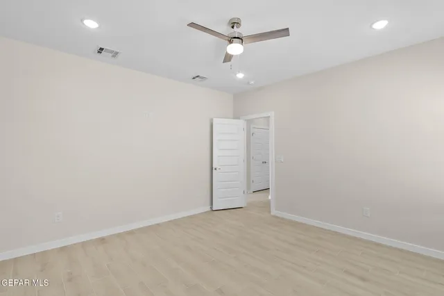 an empty room with a fan & a ceiling fan