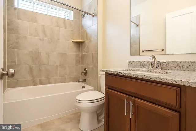 a bathroom with a granite countertop sink a toilet and shower