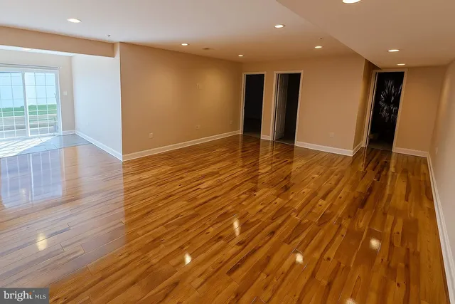 a view of an empty room with wooden floor and entryway