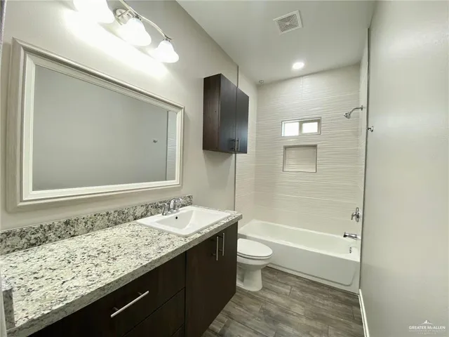 a bathroom with a granite countertop sink a toilet and shower