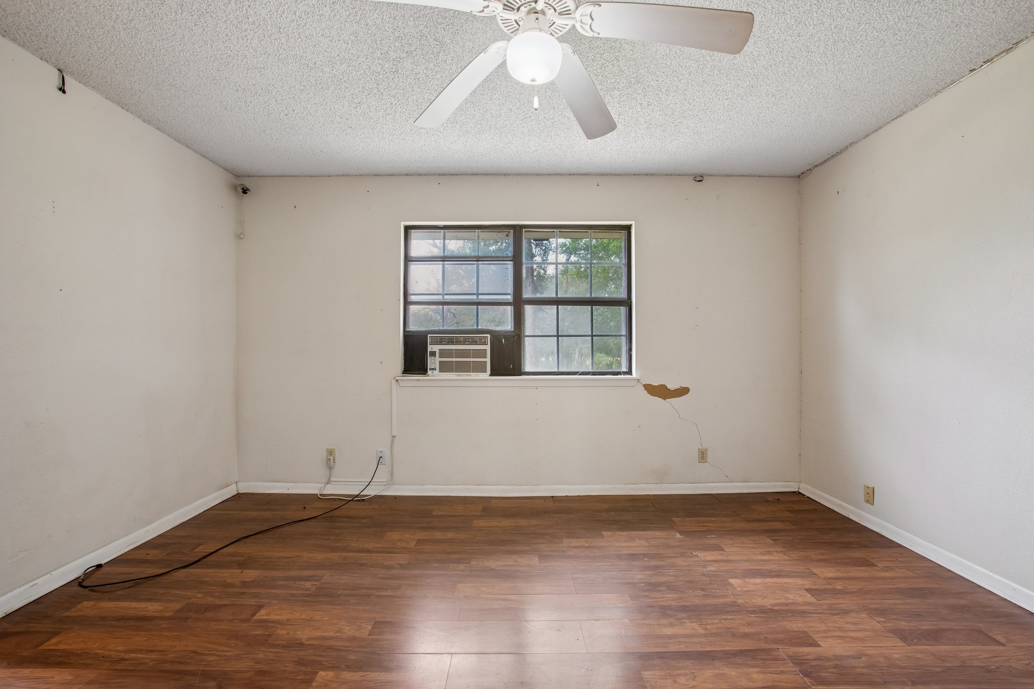 406 Monkey Road Elgin, TX 78621 - Photo 14 of 39 Room featuring wood-finish flooring, a window with exterior views, and a ceiling fan with integrated lighting