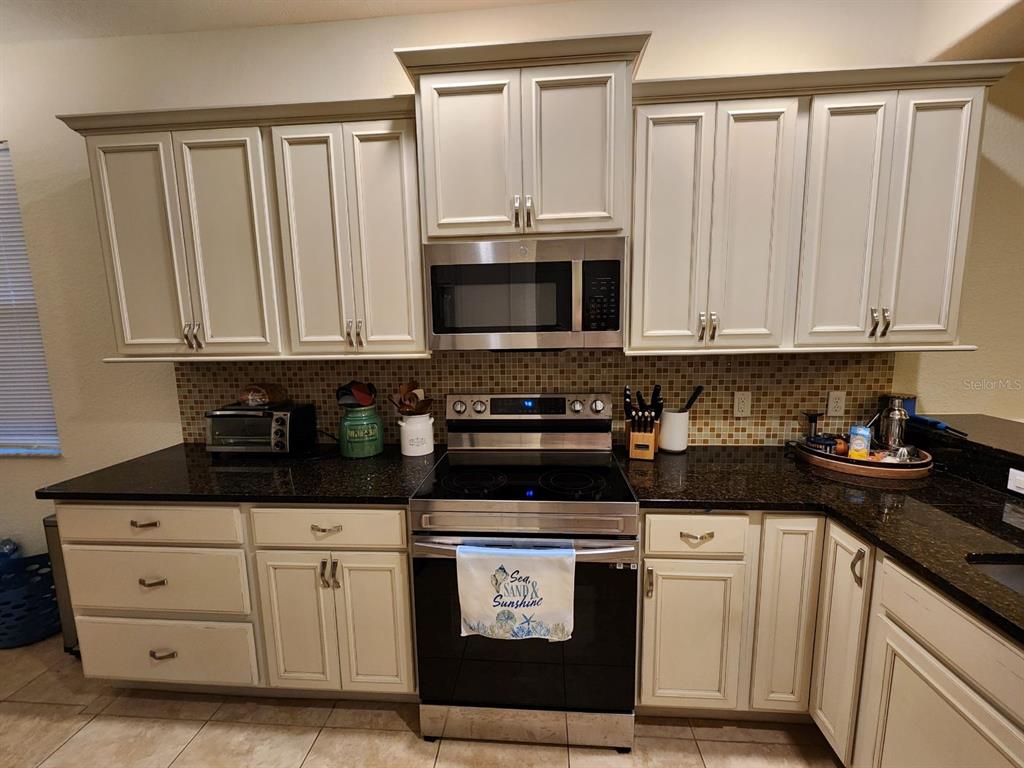 9027 Stone Harbour Loop Bradenton, FL 34212 - Photo 2 of 20 a kitchen with white cabinets and black appliances