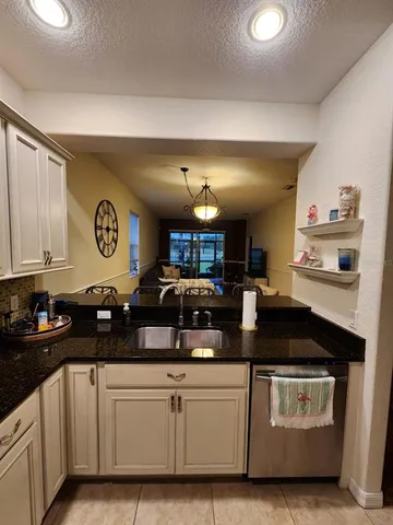 a kitchen with granite countertop a sink cabinets and stainless steel appliances