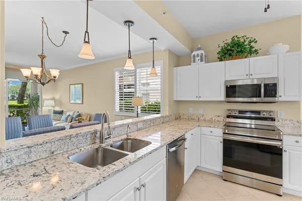 a kitchen with granite countertop a sink a stove and a microwave oven