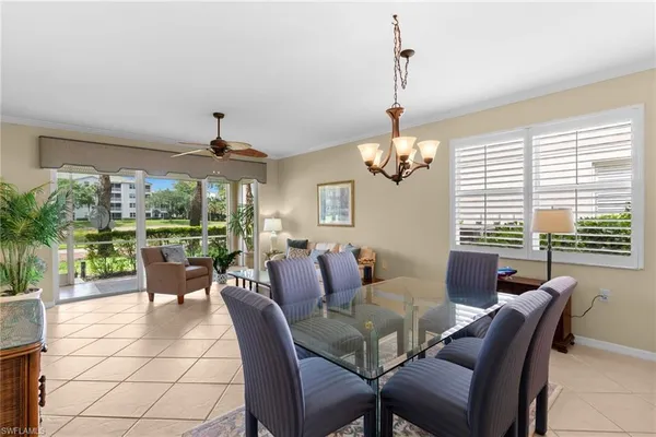 a dining room with furniture a chandelier and large windows
