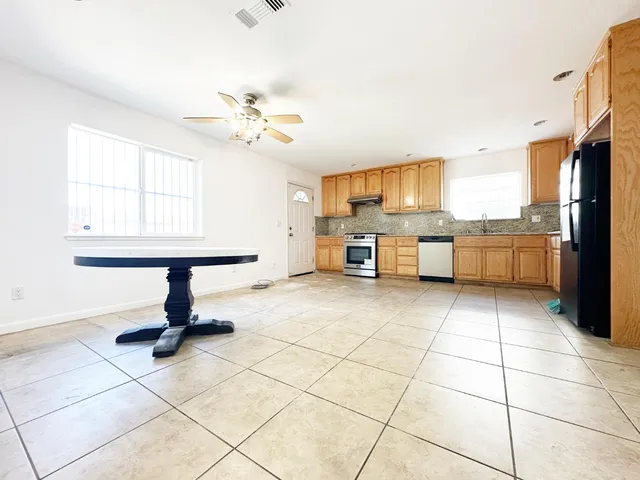 a kitchen with stainless steel appliances kitchen island granite countertop a refrigerator a stove a sink and dishwasher