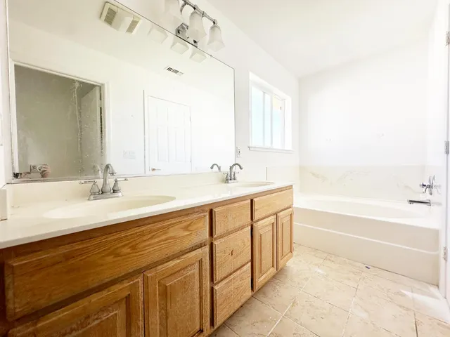 a spacious bathroom with a double vanity sink a mirror and a bathtub