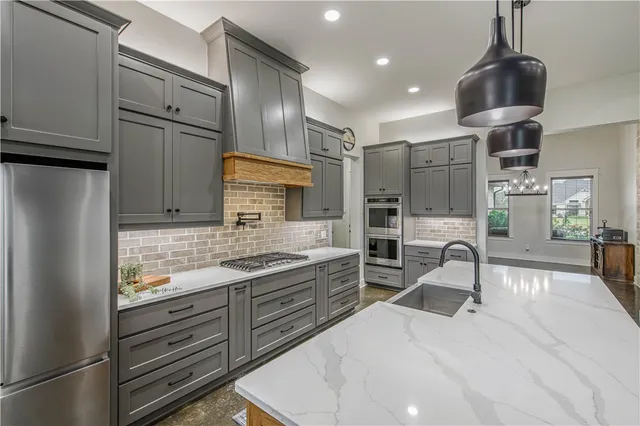 a kitchen with granite countertop a sink stainless steel appliances and cabinets