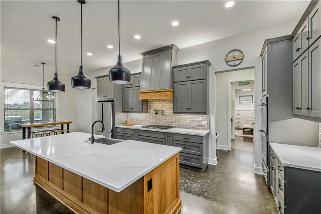 a kitchen with stainless steel appliances granite countertop a sink a stove and a refrigerator