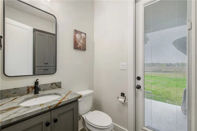 a bathroom with a granite countertop sink vanity mirror and toilet
