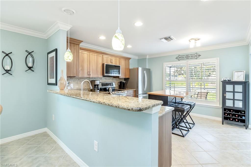 5801 Declaration Court Ave Maria, FL 34142 - Photo 9 of 38 a kitchen with granite countertop a stove a sink a microwave and wooden cabinets