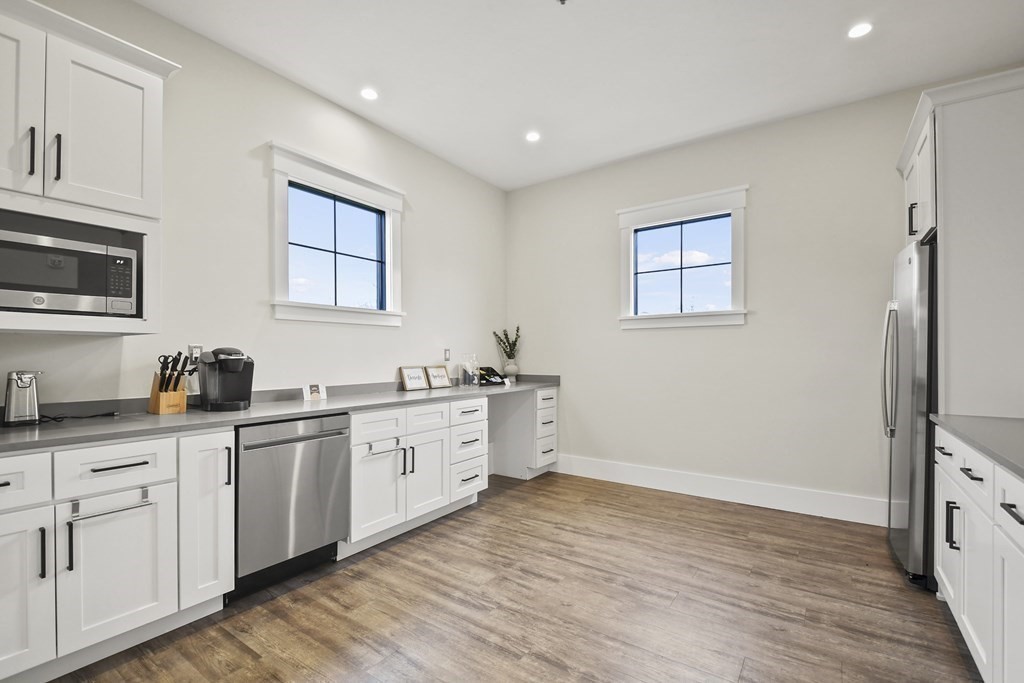 9 Eagle Lane, Unit 9 Framingham, MA 01701 - Photo 37 of 42 a large white kitchen with granite countertop a stove a sink a refrigerator and white cabinets with wooden floor