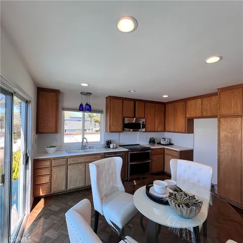 a kitchen with stainless steel appliances kitchen island granite countertop a sink dishwasher a stove a refrigerator with a dining table and chairs
