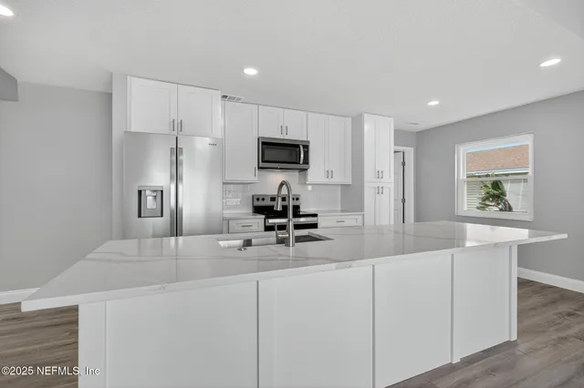 a kitchen with kitchen island a counter top space stainless steel appliances and cabinets