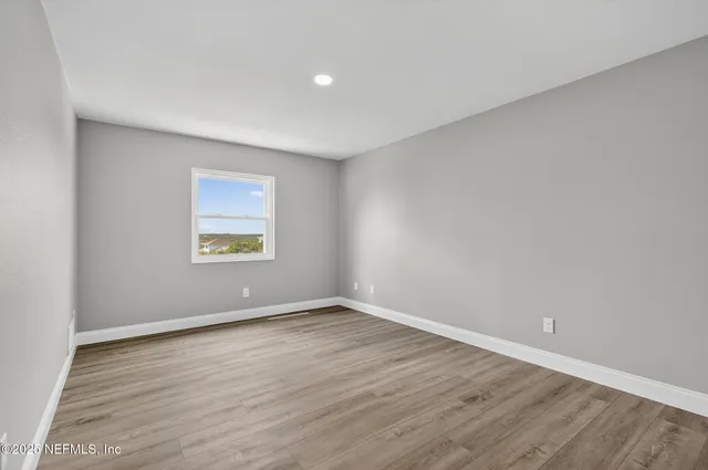 a view of an empty room with wooden floor and stairs