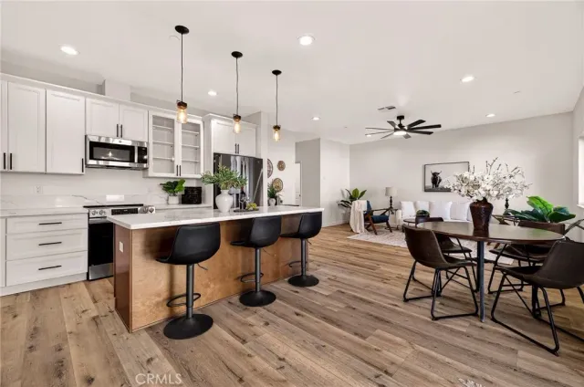 a kitchen with stainless steel appliances kitchen island granite countertop a table chairs and a wooden floor