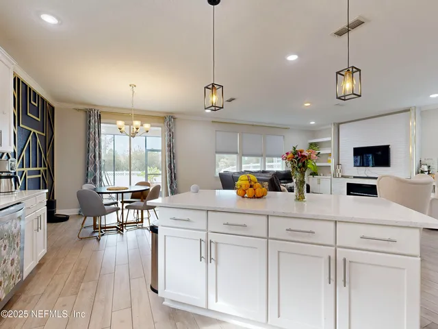 a kitchen with stainless steel appliances kitchen island granite countertop a stove a sink a dining table and chairs with wooden floor