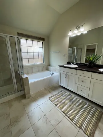 a spacious bathroom with a granite countertop sink a mirror and a bathtub