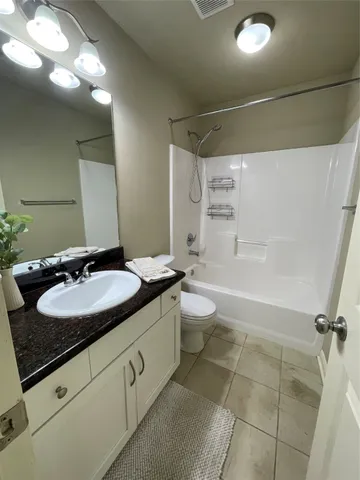 a bathroom with a granite countertop sink toilet mirror and a bathtub