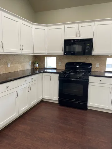 a kitchen with granite countertop white cabinets and stainless steel appliances