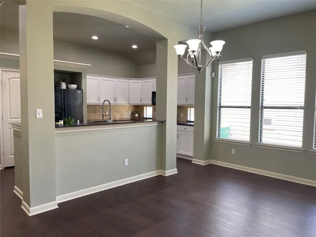 a room with kitchen island granite countertop a stove a sink a refrigerator and a large window