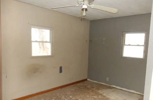 an empty room with a window and a fan