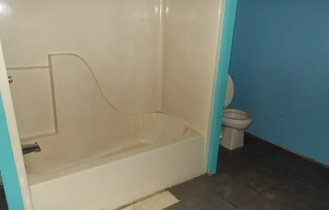 a bath tub sitting next to a white toilet and a shower