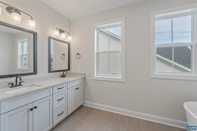 a spacious bathroom with a double vanity sink a mirror and a toilet