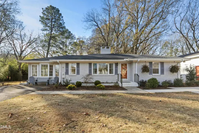 a front view of a house with a garden and trees