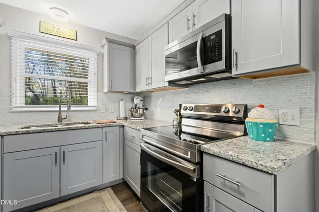a kitchen with stainless steel appliances granite countertop a sink and dishwasher a stove top oven with white cabinets