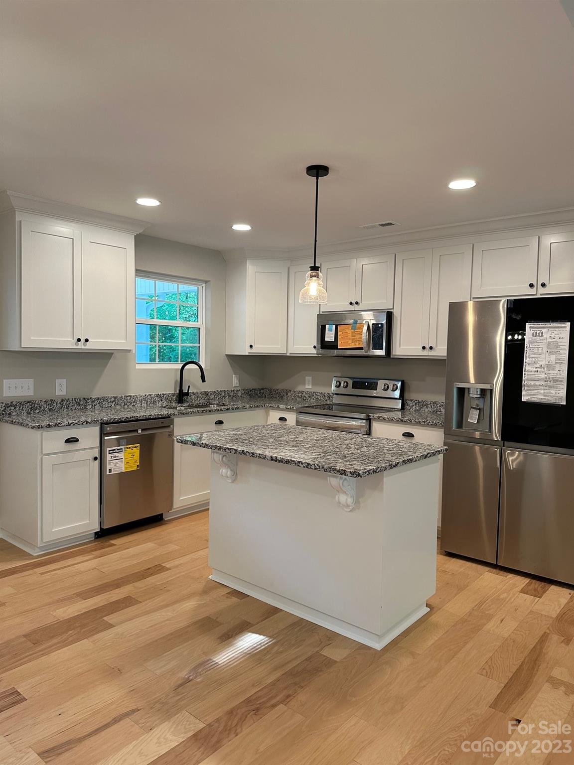 1091 Tryon Street Lancaster, SC 29720 - Photo 18 of 30 a kitchen with stainless steel appliances granite countertop a stove a sink dishwasher a refrigerator and white cabinets with wooden floor