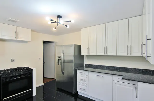 a kitchen with stainless steel appliances granite countertop a refrigerator a stove and white cabinets