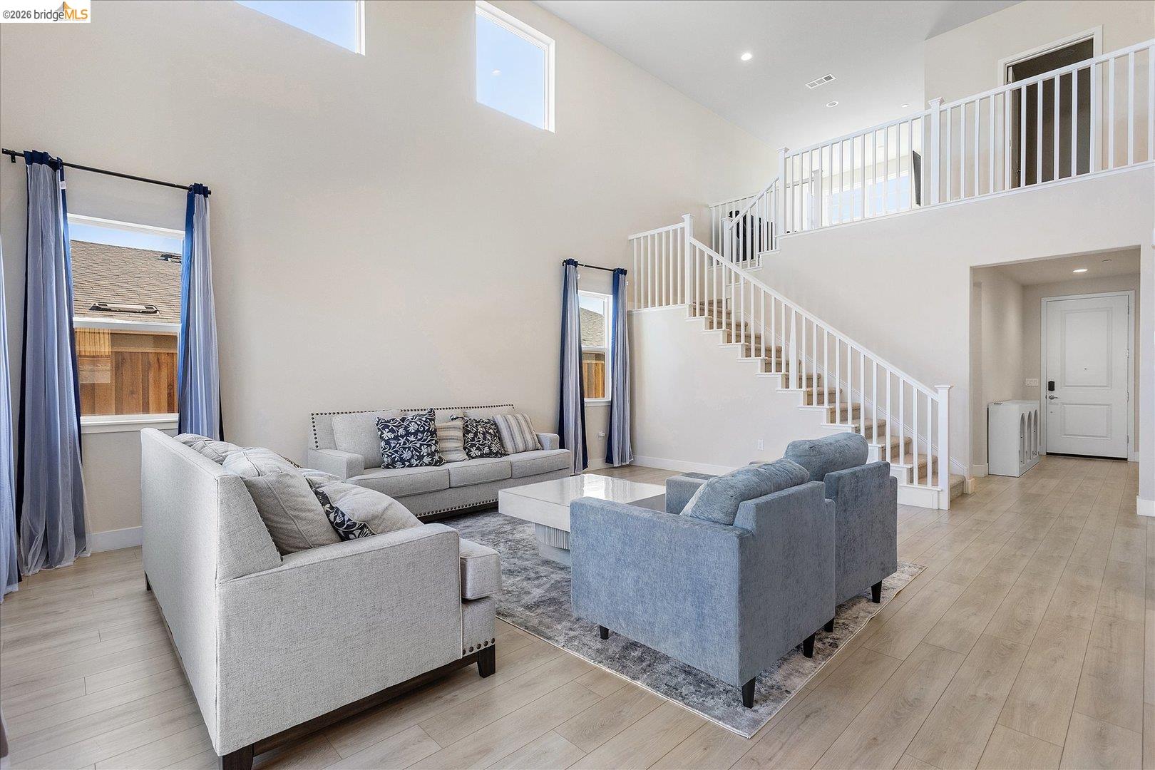 5601 Ridgepoint Way Antioch, CA 94531 - Photo 10 of 59 Two-story living area with high ceilings, light wood-finish flooring, and a prominent staircase with white railings