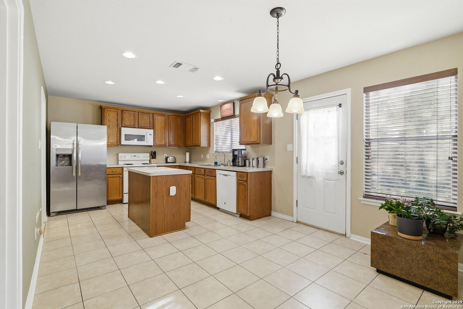 133 Falling Sun Cibolo, TX 78108 - Photo 10 of 28 a kitchen with stainless steel appliances granite countertop a refrigerator a sink dishwasher and a view of living room