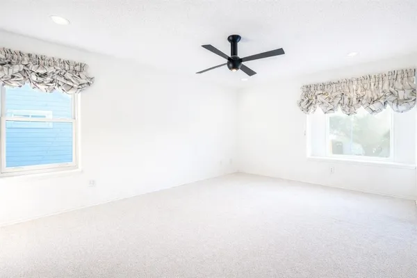 a view of a big room with a window and a ceiling fan