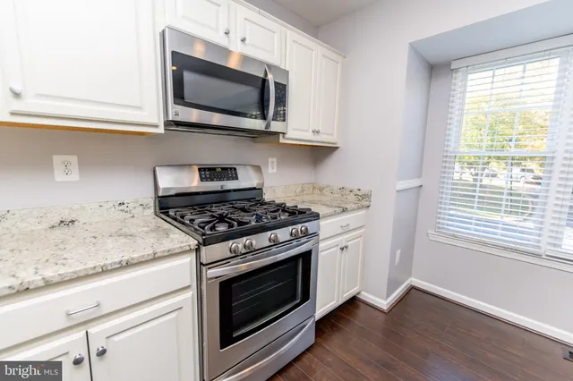 a kitchen with stainless steel appliances granite countertop a stove microwave and sink