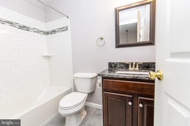 a bathroom with a granite countertop toilet sink and mirror