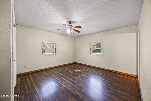 a view of an empty room with a window and wooden floor