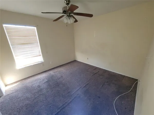 an empty room with a window and a fan