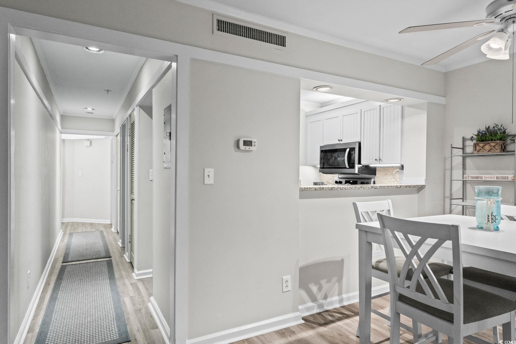 415 Ocean Creek Drive, Unit 2346 Myrtle Beach, SC 29572 - Photo 11 of 40 Kitchen featuring light wood finished floors, white cabinets, a breakfast bar area, stainless steel appliances and a ceiling fan