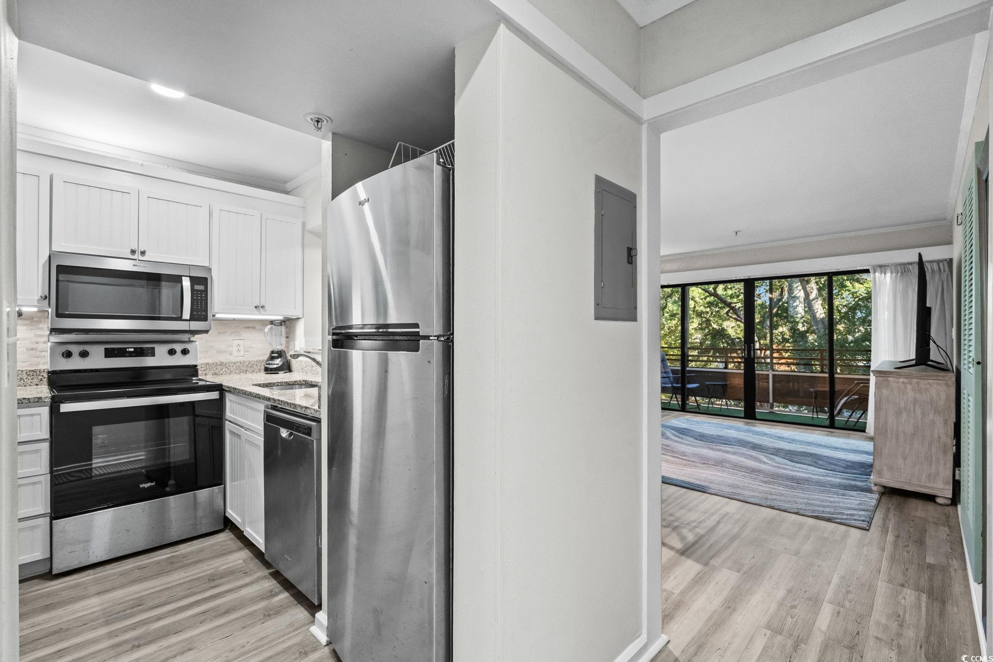 415 Ocean Creek Drive, Unit 2346 Myrtle Beach, SC 29572 - Photo 13 of 40 Kitchen with appliances with stainless steel finishes, light wood-type flooring, decorative backsplash, and light stone countertops