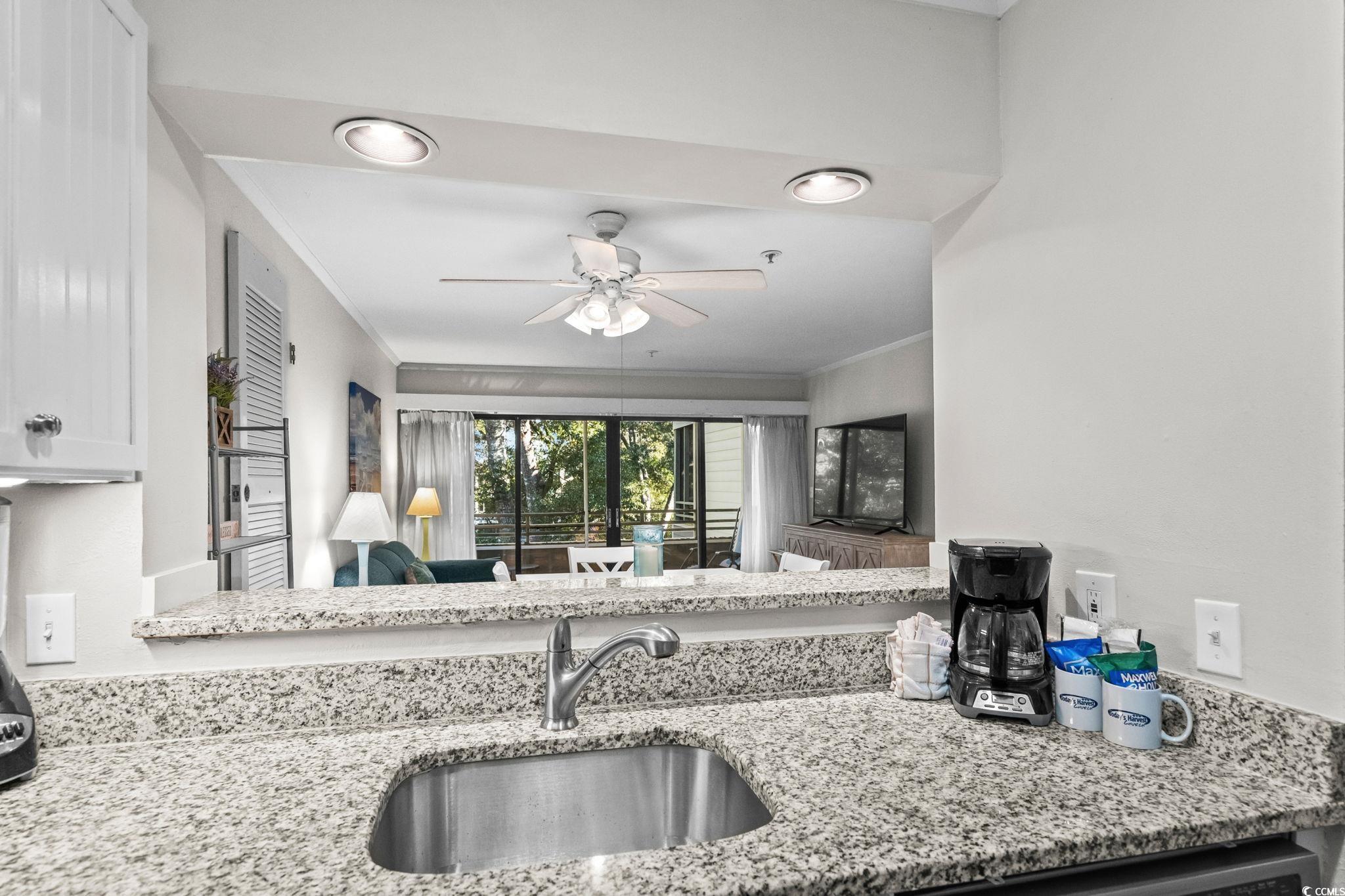 415 Ocean Creek Drive, Unit 2346 Myrtle Beach, SC 29572 - Photo 16 of 40 Kitchen featuring light stone counters, crown molding, a ceiling fan, and white cabinetry