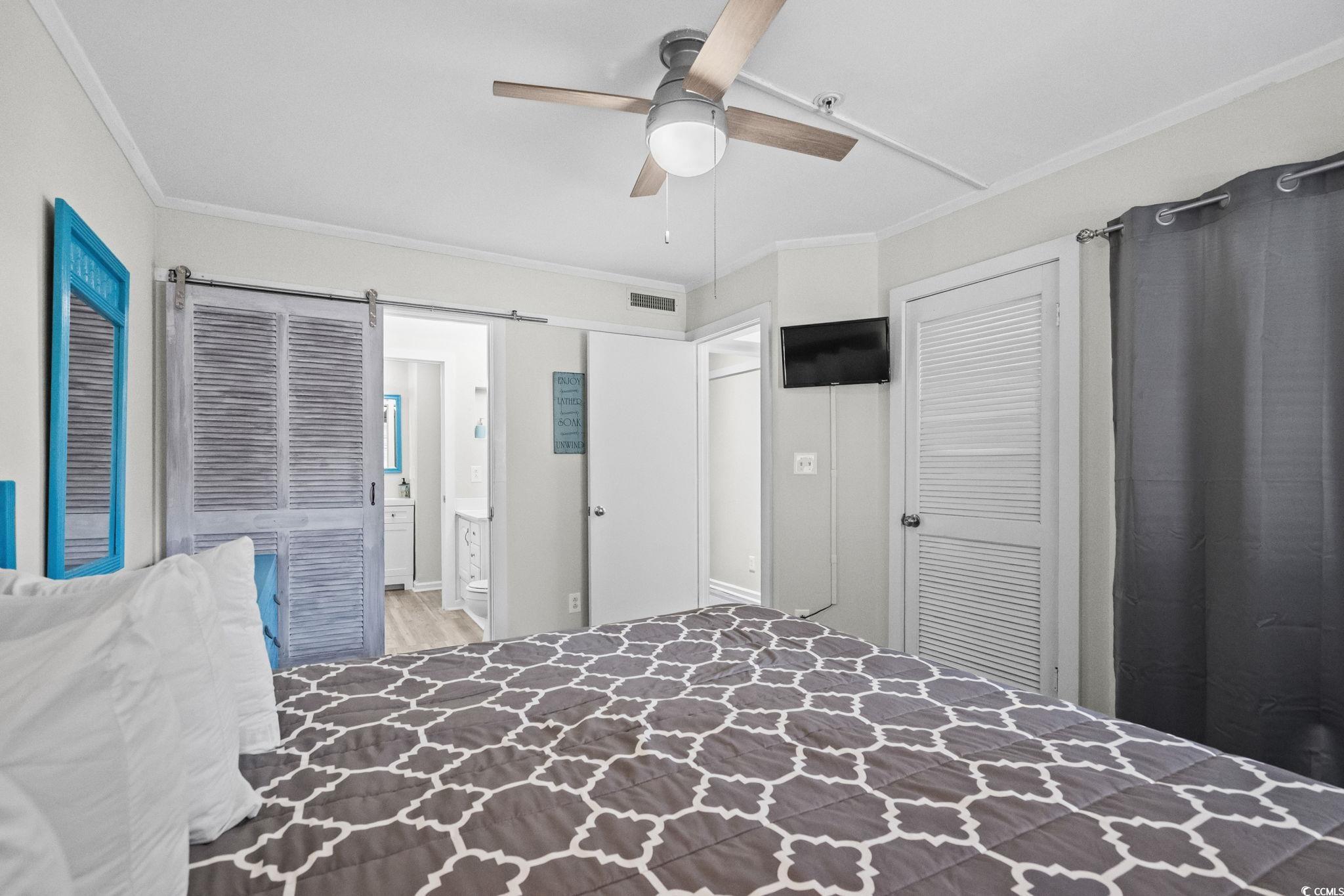 415 Ocean Creek Drive, Unit 2346 Myrtle Beach, SC 29572 - Photo 19 of 40 Bedroom with ornamental molding, a barn door, connected bathroom, ceiling fan, and a closet