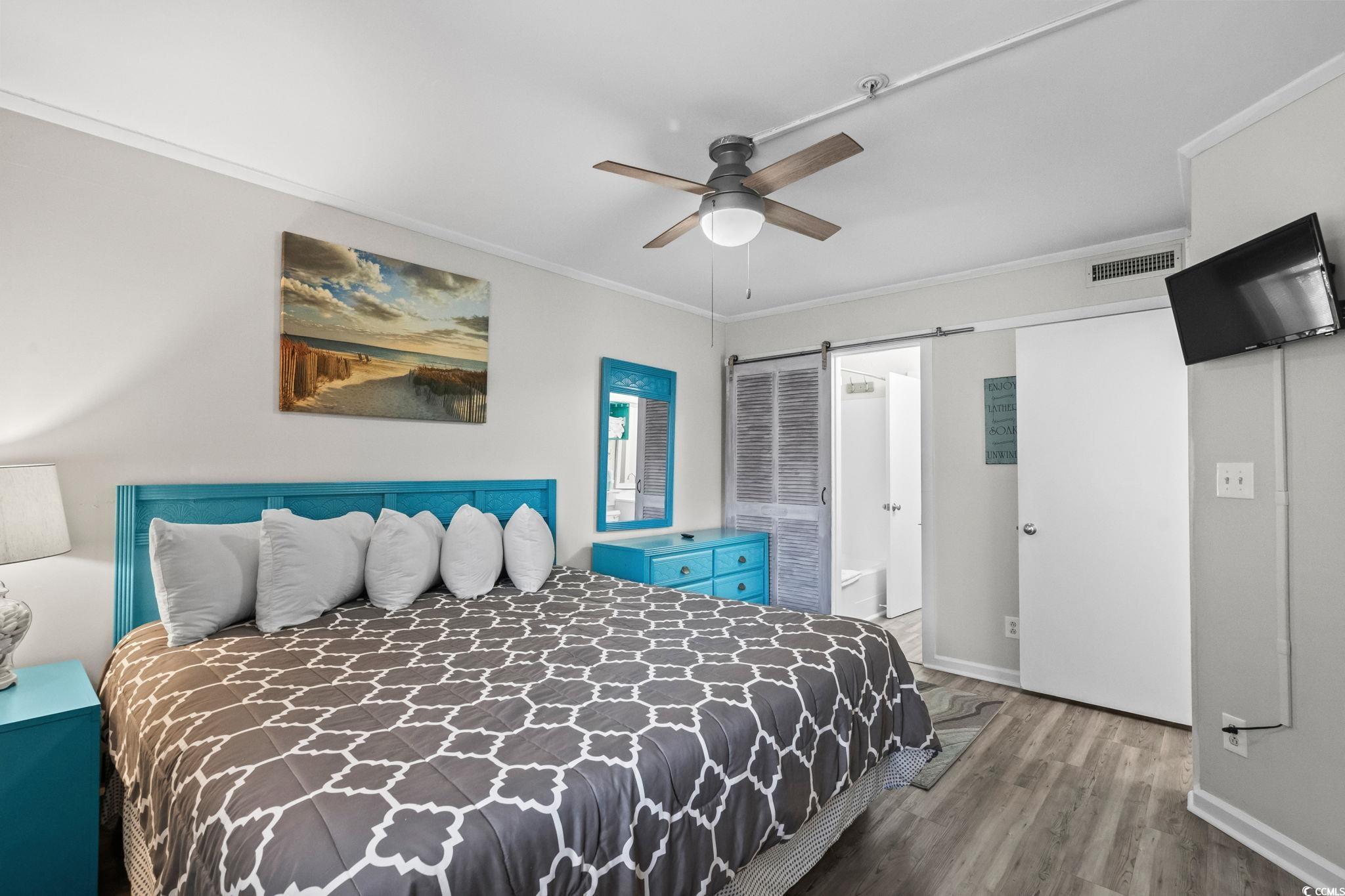 415 Ocean Creek Drive, Unit 2346 Myrtle Beach, SC 29572 - Photo 20 of 40 Bedroom featuring wood finished floors, crown molding, a barn door, a ceiling fan, and a closet