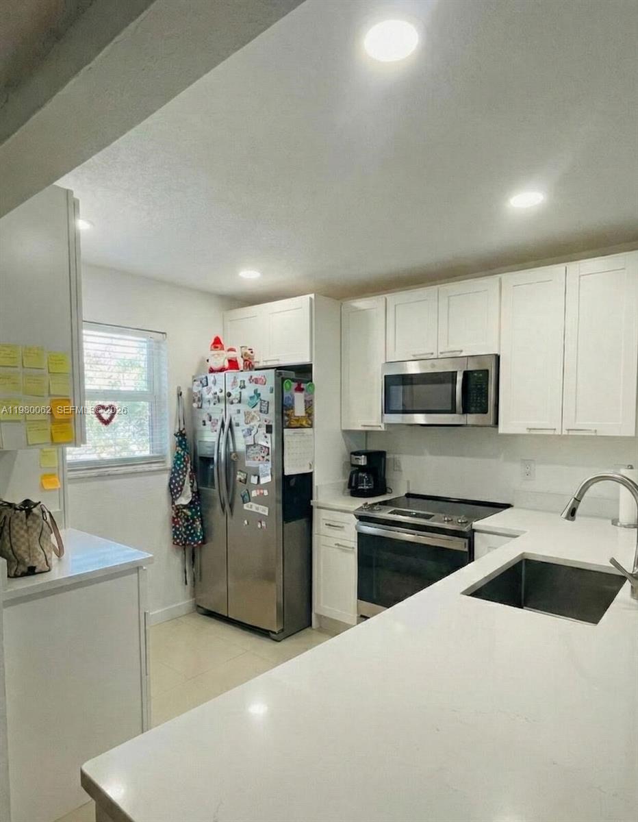 100 Ashbury Road, Unit 305 Hollywood, FL 33024 - Photo 2 of 8 a kitchen with stainless steel appliances a refrigerator sink and stove top oven