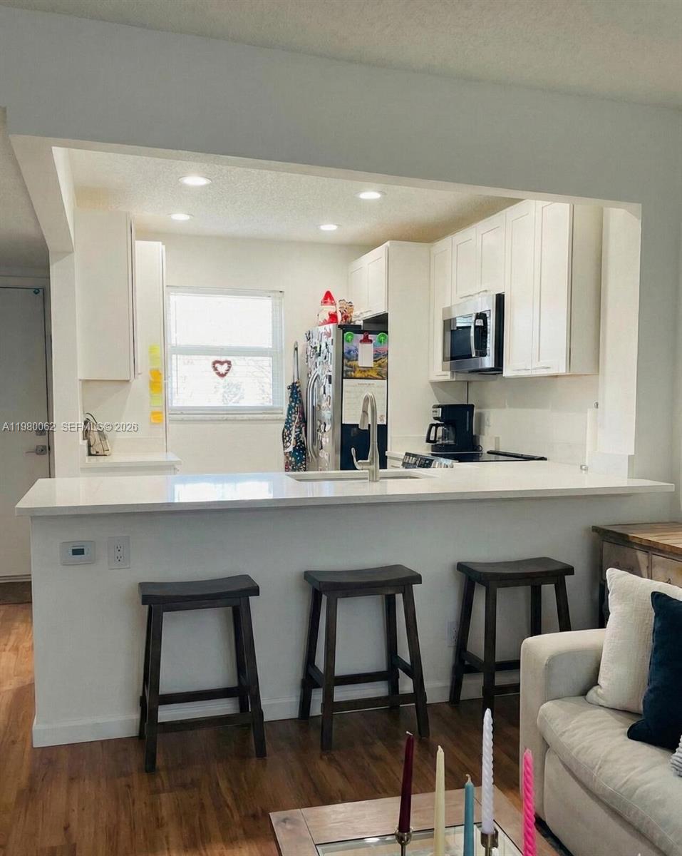 100 Ashbury Road, Unit 305 Hollywood, FL 33024 - Photo 3 of 8 a kitchen with a table chairs sink and cabinets