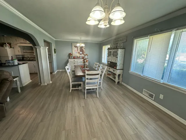 a dining room with furniture a chandelier and wooden floor